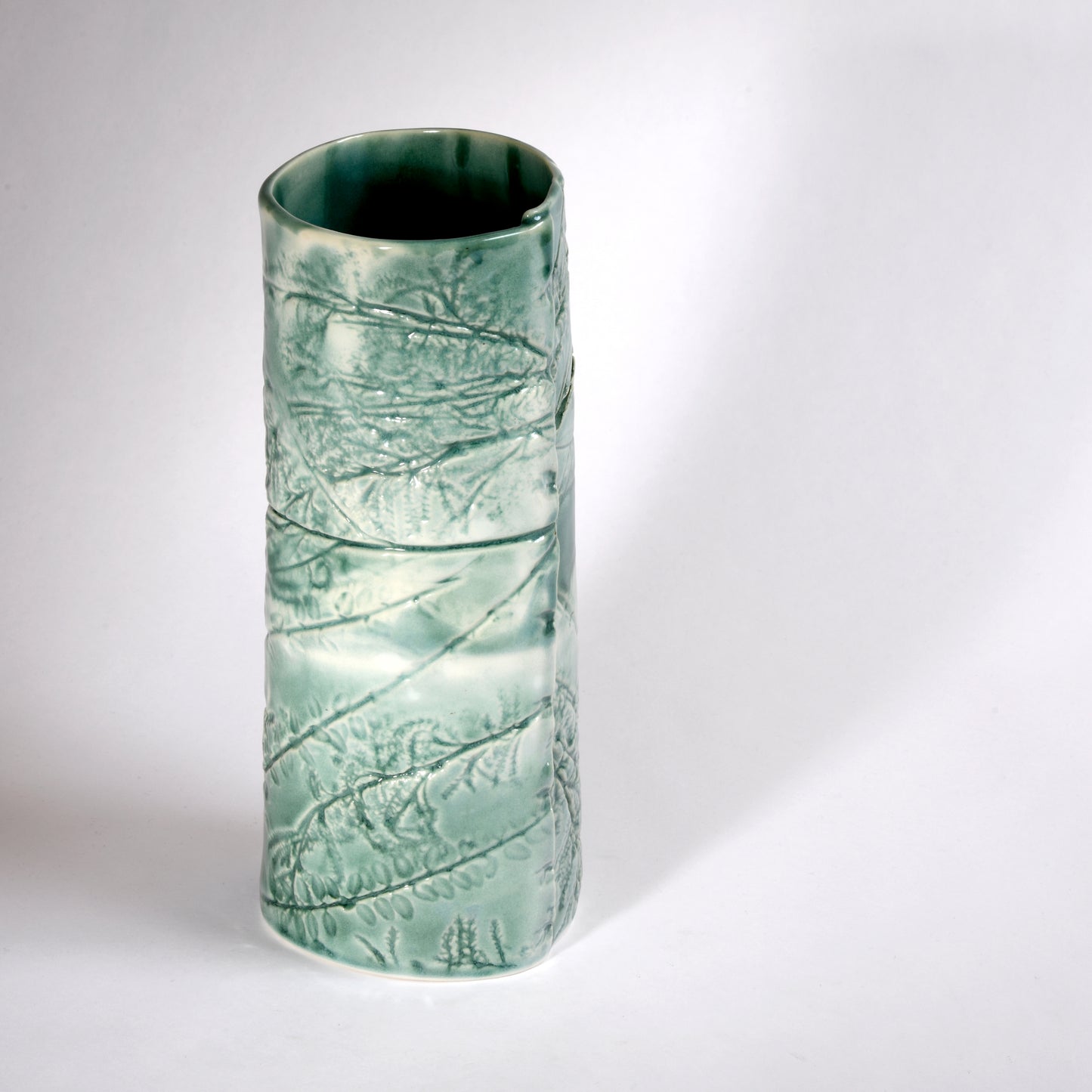 A very slightly leaning vase with an organic "windswept" design in a beautiful aqua glaze