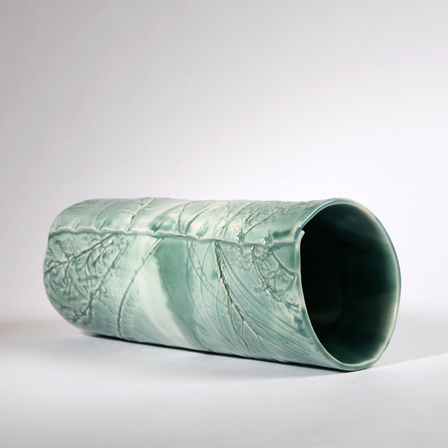 A very slightly leaning vase with an organic "windswept" design in a beautiful aqua glaze