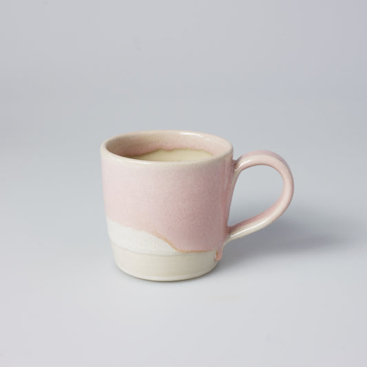 A beautiful wheel thrown Mug made by Hannah and inspired by the coast, in a subtle pink and chalk colour.   The glaze on each mug is hand poured so your cup will be like those in the pictures but each one is unique.   Dimensions approx |  Height: 10cm     Diameter: 9.5cm  Volume | 350ml